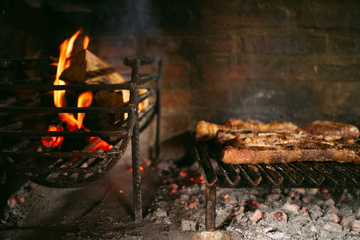 Meat grilling over an open wood fire (representative of a gourmet BBQ, not the Colonel's Homestead kitchen)